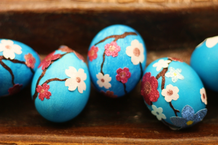 fünf blaue Eier mit kleinen Frühlingsblumen als Motive, Ostereier färben