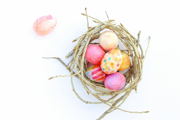 Ostereier färben und mit Papier umhüllen in ein Nest aus Stöcken legen