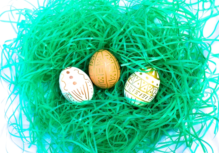 in einem Nest liegen drei Ostereier mit goldener Farbe bemalt, Ostereierfarbe
