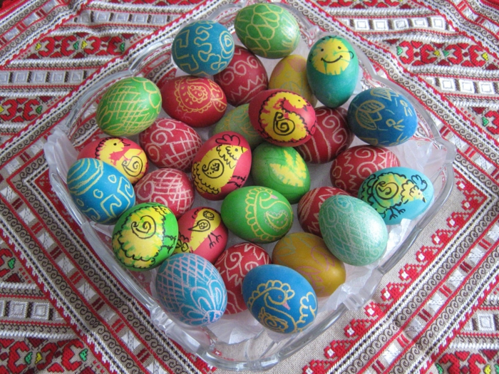 kleine Küken in gelber Farbe, Ostereierfarbe rote, grüne und blaue Eier mit Motiven