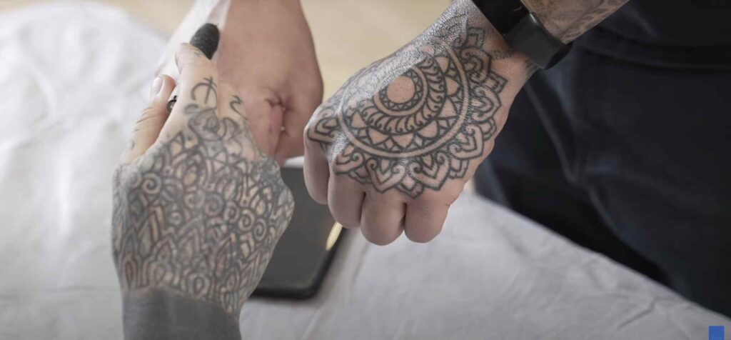 A man is showing his hand to a tattoo artist for applying the tattoo.